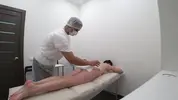массажист делает клиентке массаж с маслом